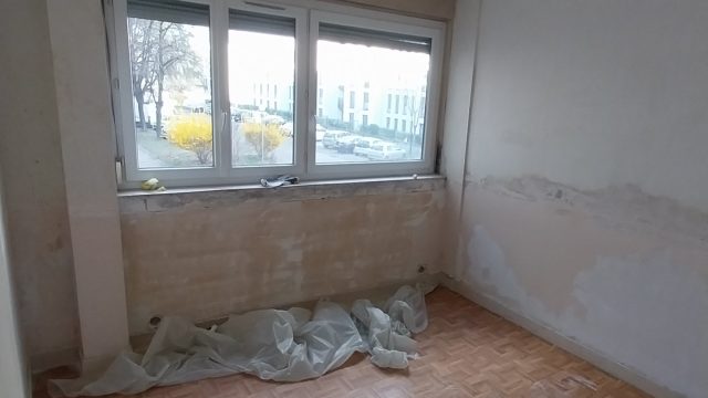 Chambre avant travaux, murs abîmés au pied de la fenêtre
